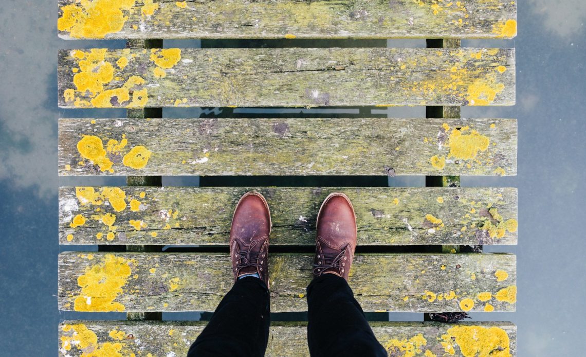 pair of brown leather shoes standing on grey and yellow bridge