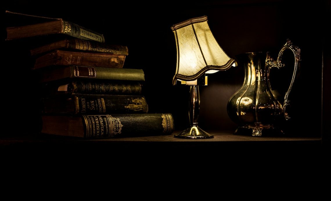 turned on desk lamp beside pile of books