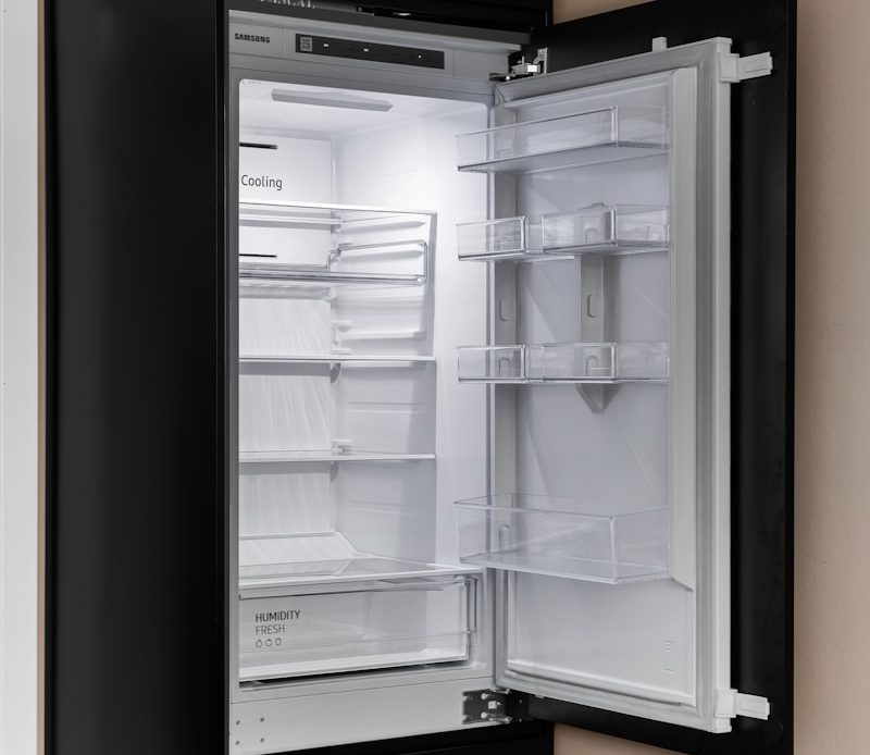 A black refrigerator with its door open in a kitchen