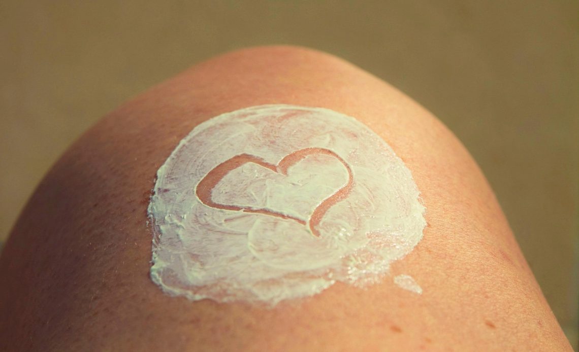 Vrouw smeert voorzichtig een kalmerende lotion op een zonverbrande schouder