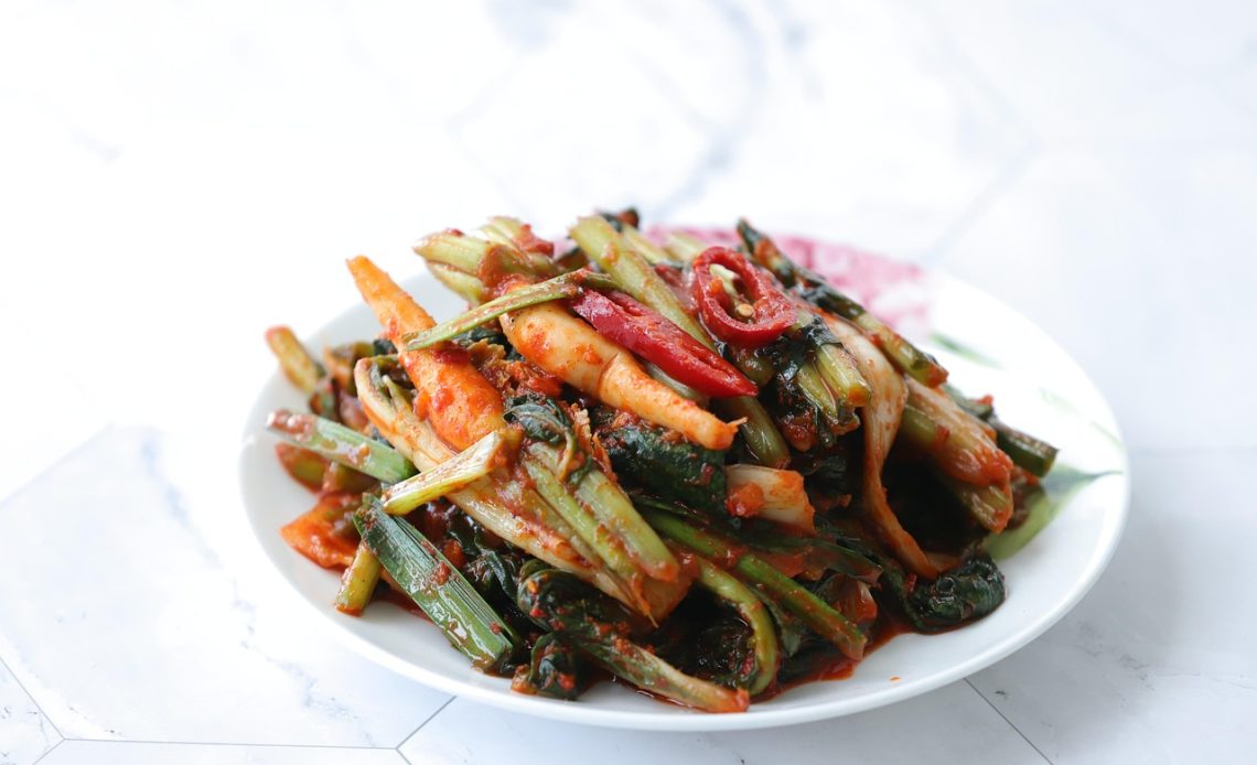 Gefermenteerde voeding zoals kefir en kimchi op een houten tafel, goed voor de darmflora bij hitte in de zomer