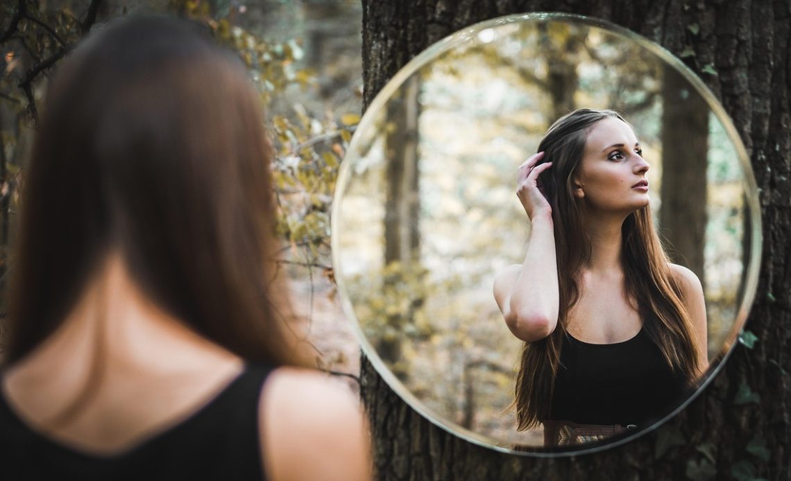 Vrouw die haar hoofdhuid bekijkt in de spiegel om symptomen te herkennen