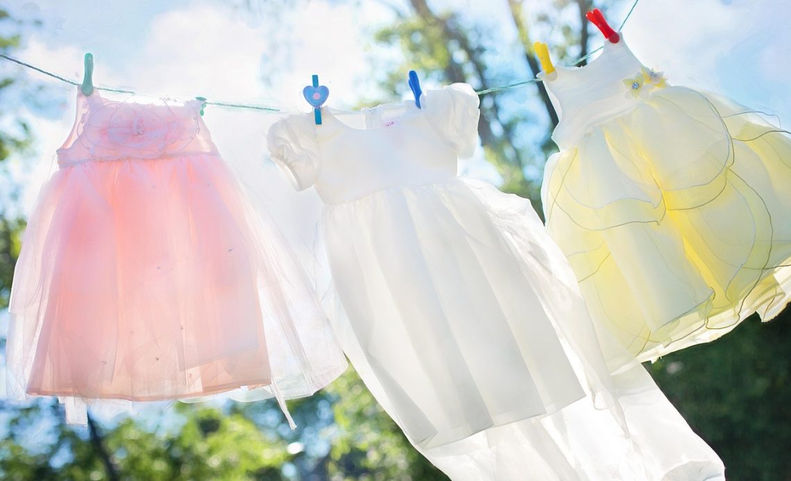 Kleding met waslabels naast een wasmachine