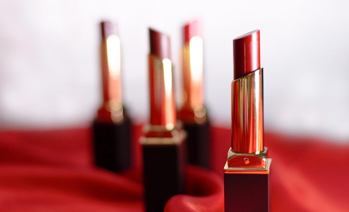 Een vrouw die matte lippenstift opdoet in een warme herfsttint, met een goed gehydrateerde liphuid
